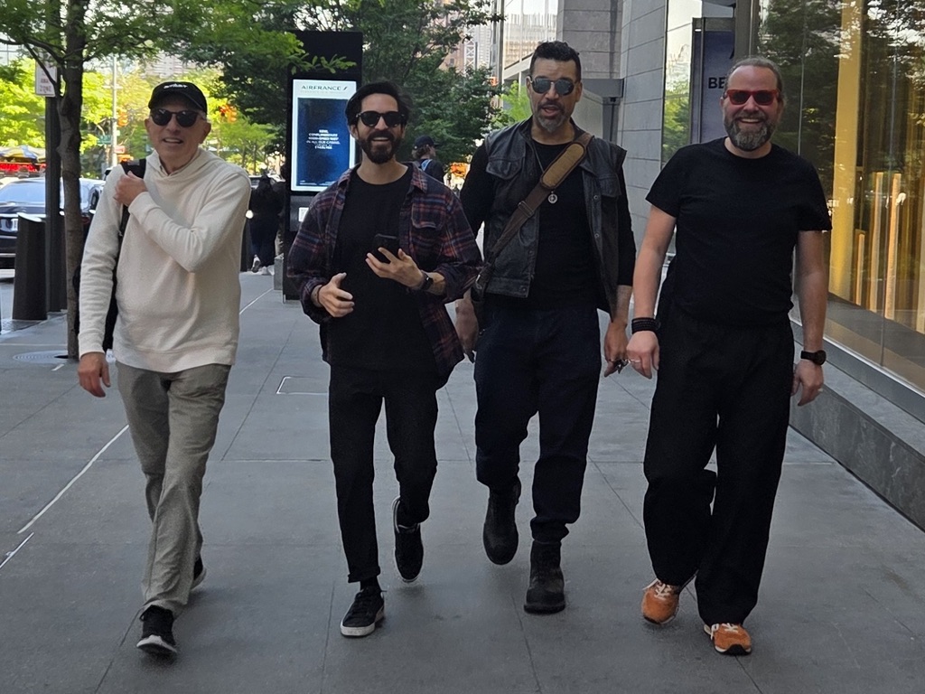 Perry walking with three collaborators on a city sidewalk