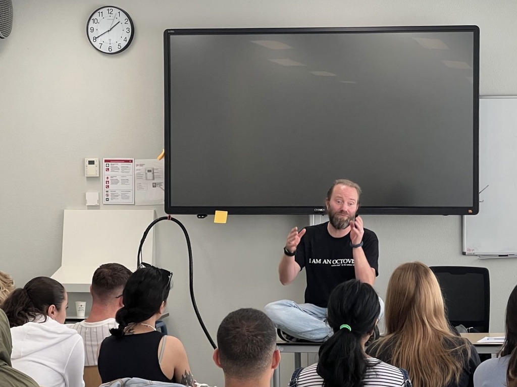 Perry teaching a classroom wearing 'I am an Octover' shirt