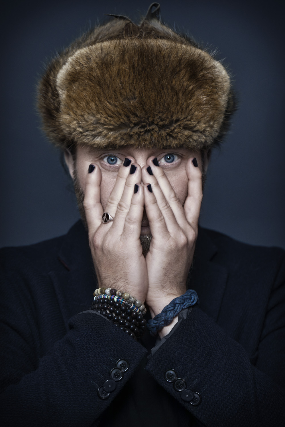 Perry with fur hat, hands covering face, eyes peeking through
